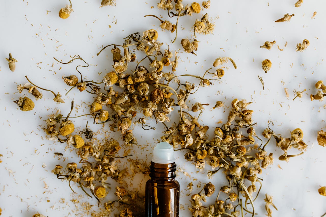services-01 Aromatic dried chamomile flowers scattered around a minimalistic essential oil bottle.